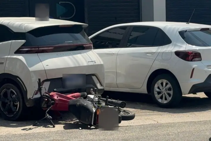 BYD branco estacionado na vaga, com uma moto caída encostada na traseira